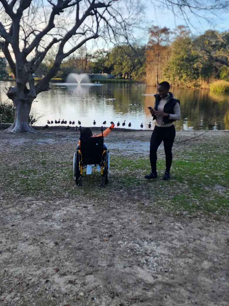Justus raising an arm high in celebration from his wheelchair at the lakeside.