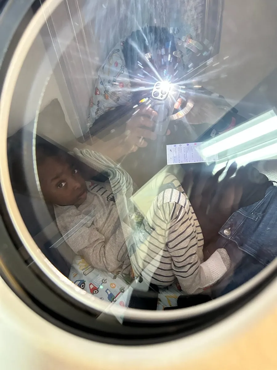 Justus looking out through the porthole of a hyperbaric oxygen chamber.