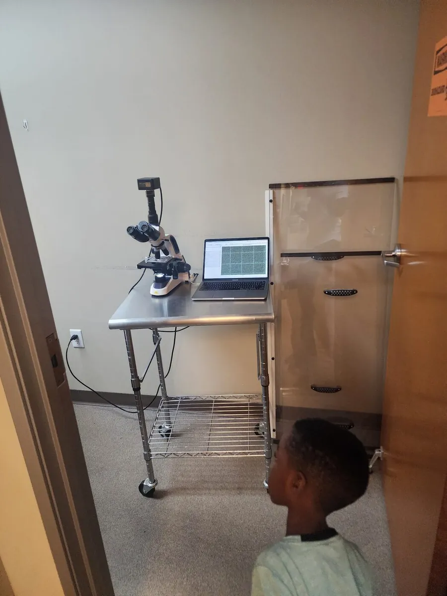 Justus looking up at a microscope during a treatment visit.